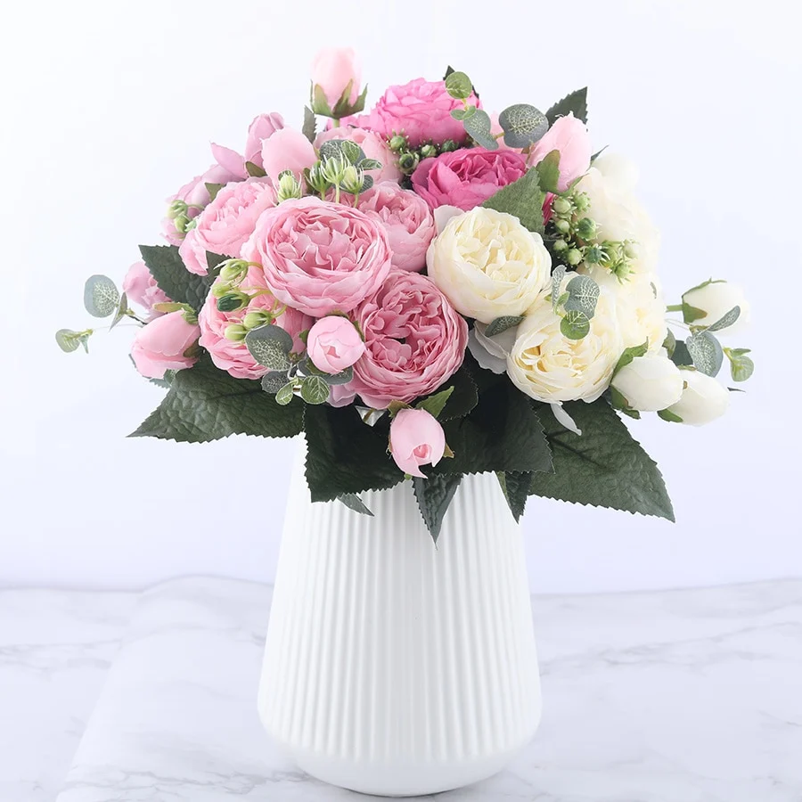 Bouquet de fleurs de pivoines artificielles roses et crème dans un vase blanc côtelé sur fond blanc