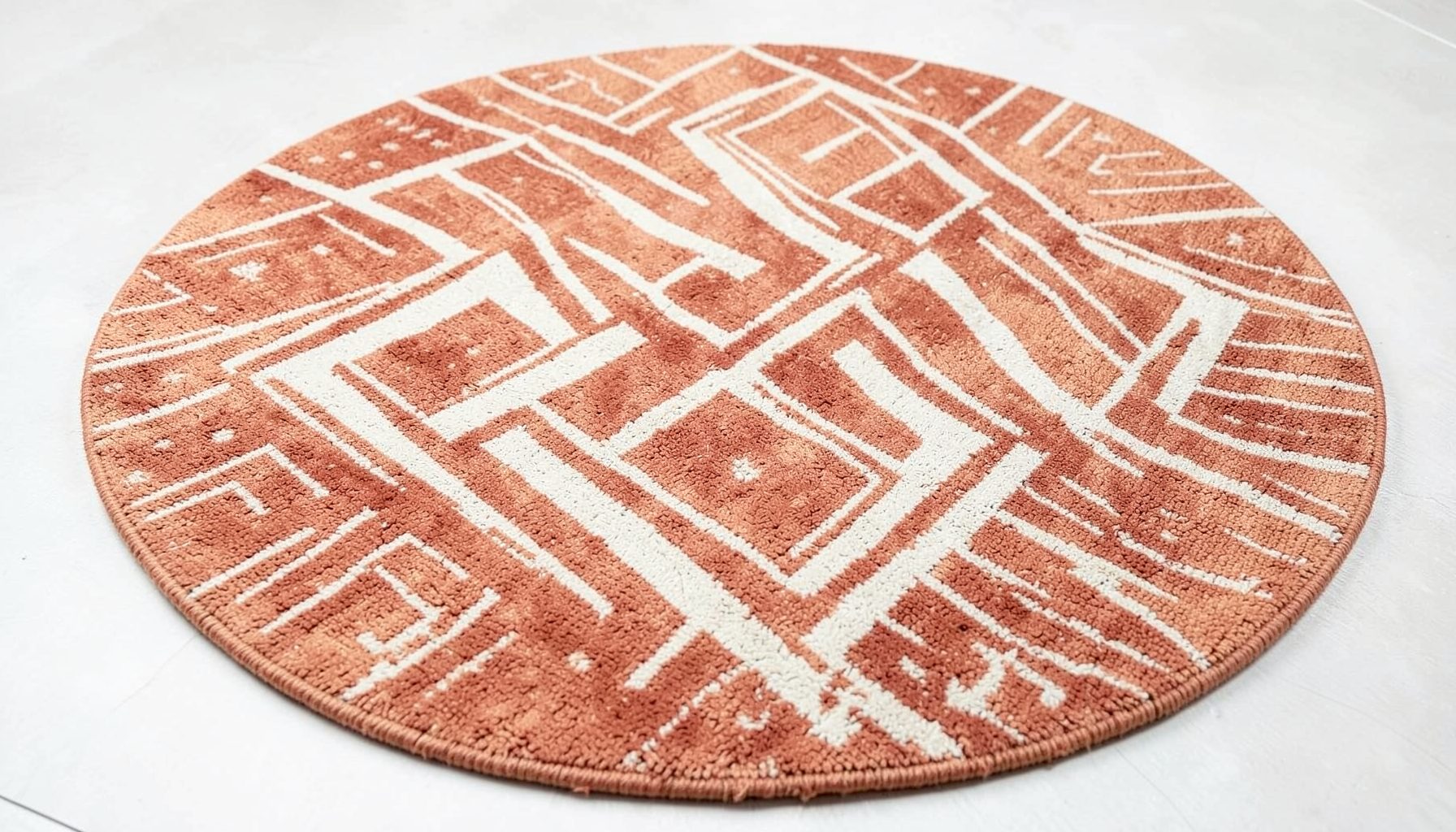 Tapis scandinave rond modèle Oppland avec motifs géométriques en chevrons et lignes, tons chauds terracotta et crème